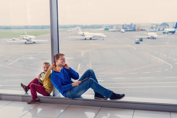 Father and son waiting to board in airport - Фото, изображение