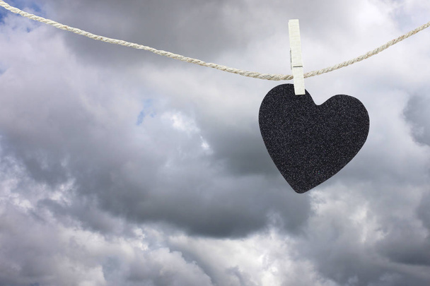 Papier Black Heart accroché à une corde de chanvre marron sur les nuages de pluie ba
 - Photo, image