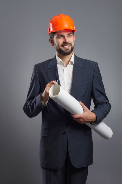 smiling handsome businessman in orange helmet with blueprint - Photo, Image