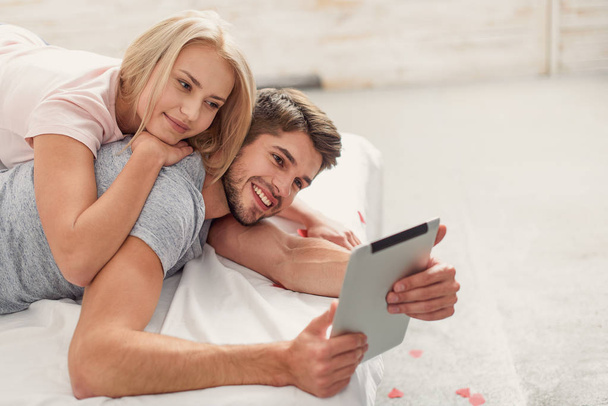 Happy man and woman using computer in bedroom - Photo, Image