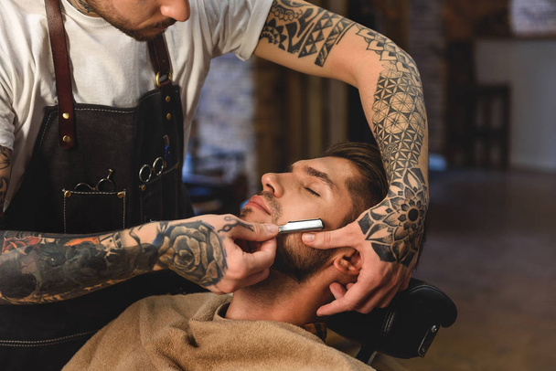 old razor in tattooed hands of stylist - Foto, imagen