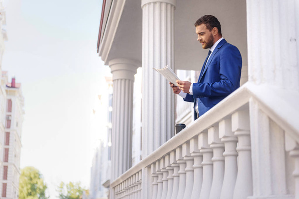 elegant mature guy with a paper on the terrace - Foto, Imagen