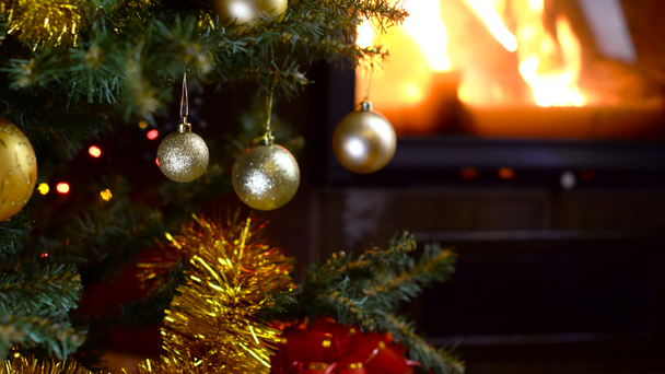 διακοσμημένο χριστουγεννιάτικο δέντρο με φώτα μπροστά στο τζάκι - Πλάνα, βίντεο