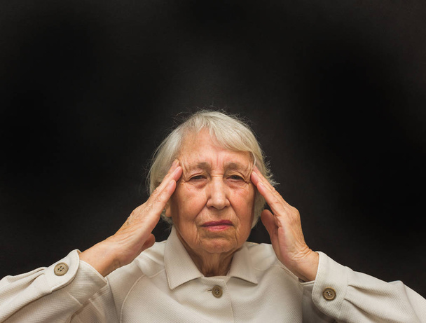 Seniorin mit Kopf in den Händen sieht müde aus - Foto, Bild