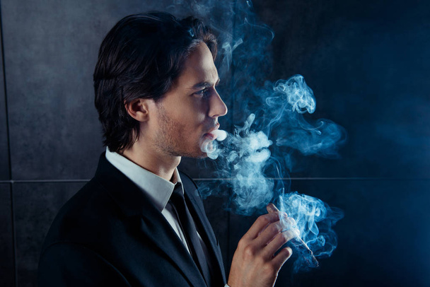 Side view photo of brutal handsome man  smoking a cigar - Foto, afbeelding