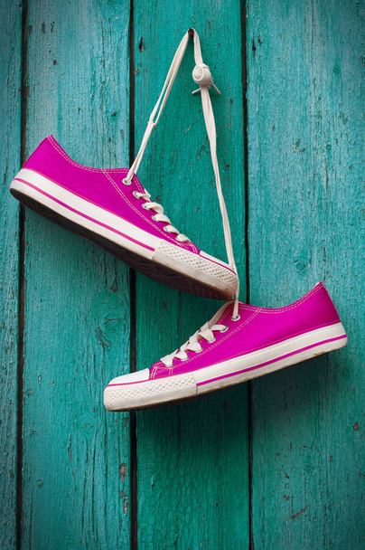 par de zapatillas de deporte de color rosa brillante colgando de un cordón
  - Foto, imagen