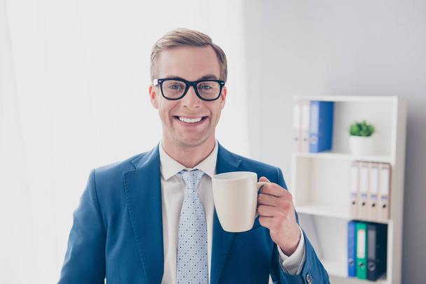 Portrait of happy smiling businessman in glasses holding cup of  - Фото, изображение