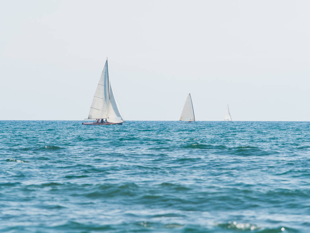 kolme pientä purjeveneitä purjehdus aurinkoisena päivänä
 - Valokuva, kuva