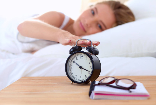 Young sleeping woman and alarm clock in bedroom at home - Foto, immagini