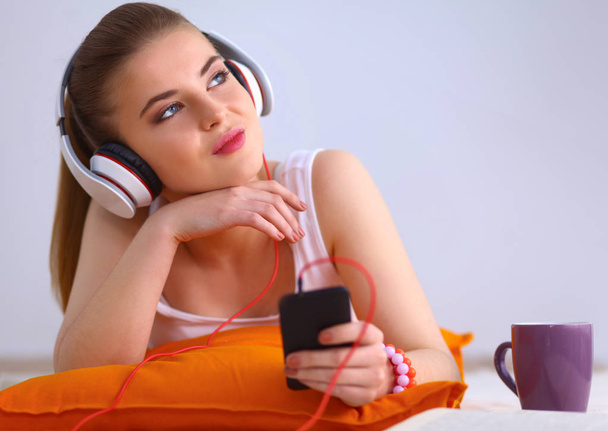 Young woman lying on floor and listen to music - Foto, Imagen