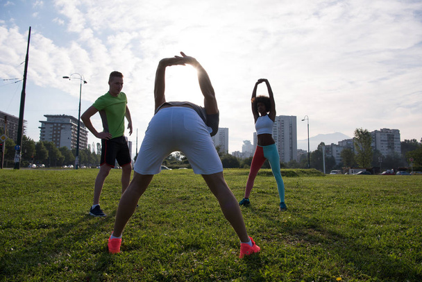 multiethnic group of people stretching in city park - Foto, Imagen