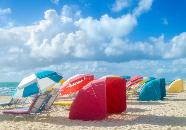 Barevné pláže slunečníky/slunečníky a chatky v blízkosti oceánu - Fotografie, Obrázek