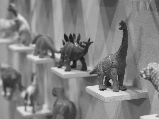 Plastic dinosaur toys on display shelves, black and white color - Photo, Image
