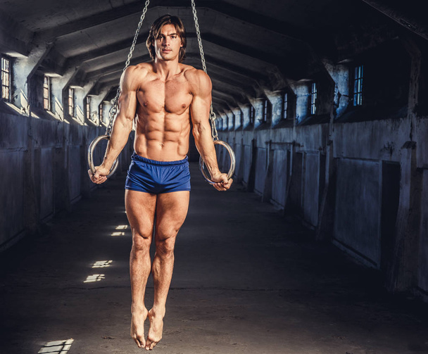 Homme musculaire posant avec des anneaux de gymnastique
 - Photo, image