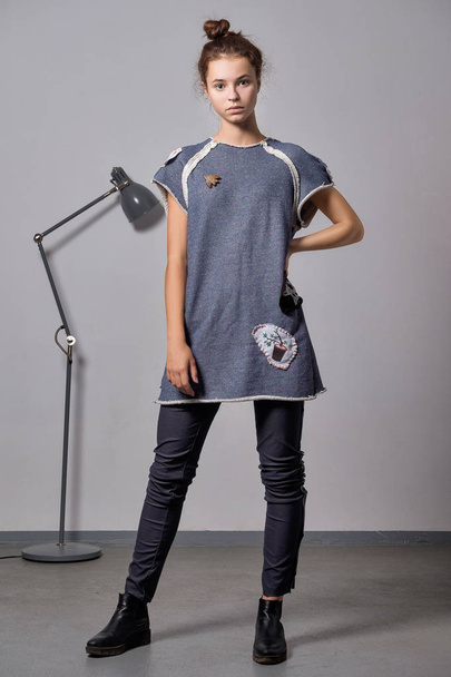 Modelo de moda muito jovem em roupas de lã quente posando perto de lâmpada de assoalho de metal
 - Foto, Imagem