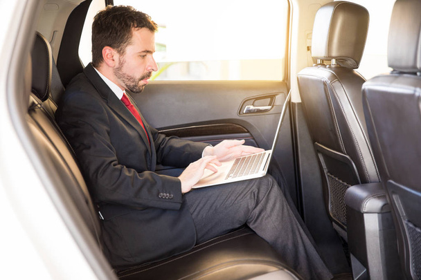 Businessman using laptop in a car - Photo, Image