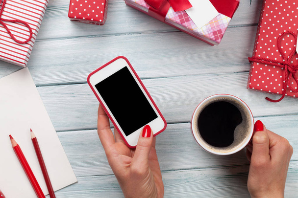 Frau hält Smartphone in der Hand und verpackt Geschenke - Foto, Bild