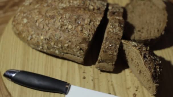 Ψωμί κομμένα σε μεγάλα κομμάτια, γυρίζοντας σε ένα δίσκο. το μαχαίρι του ψωμιού είναι μεγάλη. πάνω σε ψωμί πασπαλισμένα με σπόρους, που δίνει μια πολύ καλή γεύση. - Πλάνα, βίντεο