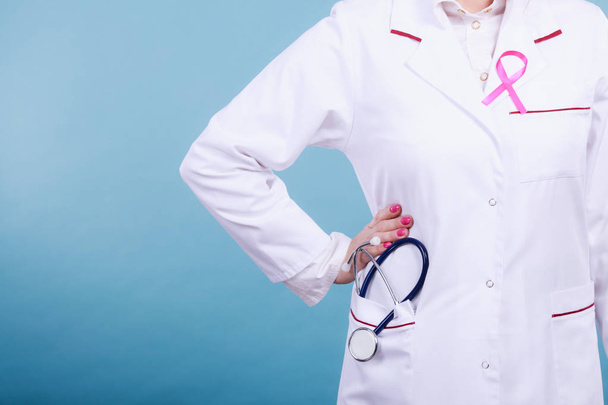 Pink ribbon with stethoscope on medical uniform. - 写真・画像