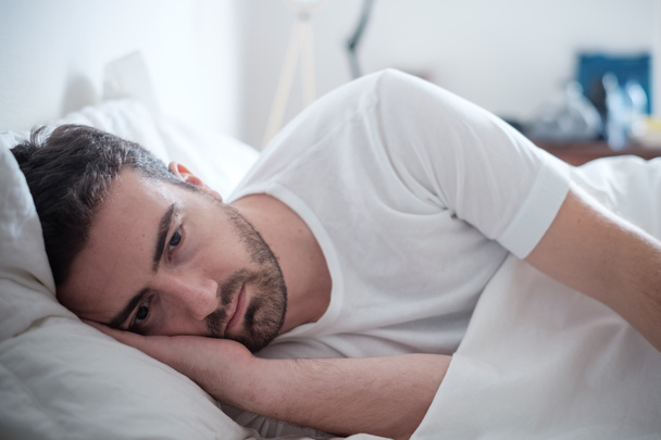 Depressed man lying in his bed and feeling bad - Photo, Image
