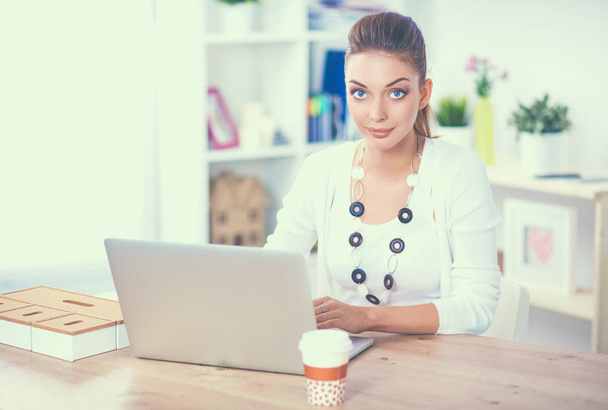 Atraktivní podnikatelka sedící na stole s laptopem v kanceláři - Fotografie, Obrázek
