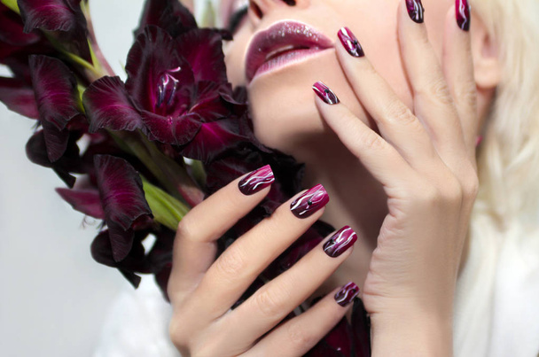 Burgundy manicure with gladiolus. - Photo, Image