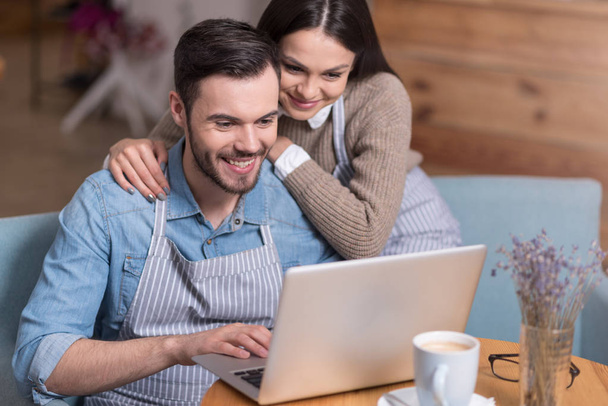 Happy couple smiling and using laptop. - 写真・画像