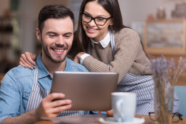 Delighted couple smiling and using tablet. - Foto, imagen