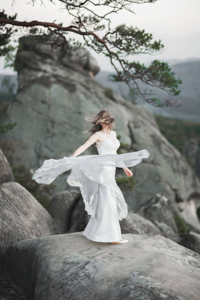 Gorgeous bride in elegant dress holding bouquet posing near forest - Valokuva, kuva