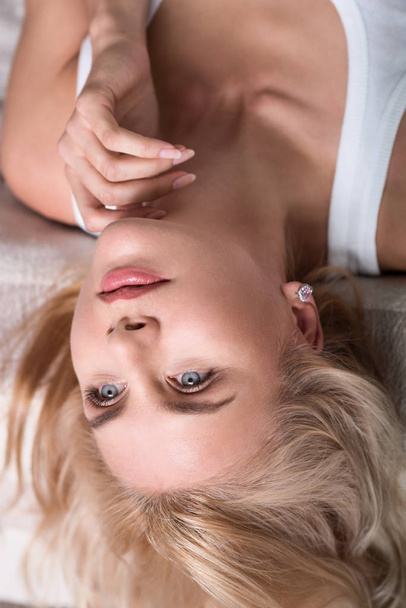Close up of blond woman lying on bed - Фото, изображение