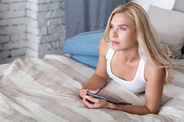 woman lying on bed with tablet - Фото, зображення