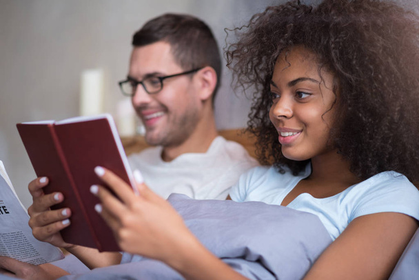 Happy couple reading together in bed - Φωτογραφία, εικόνα