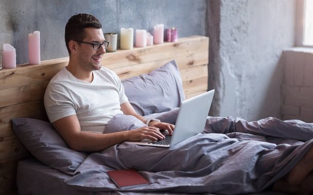 man lying in a bed with his laptop - Foto, immagini