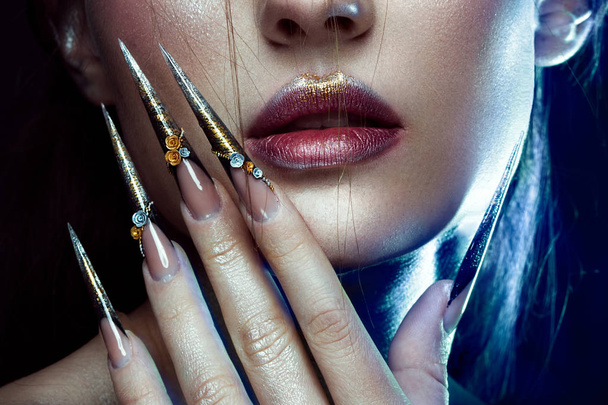 Beautiful girl with creative golden and silver glitter make-up, long nails art. beauty face. - 写真・画像