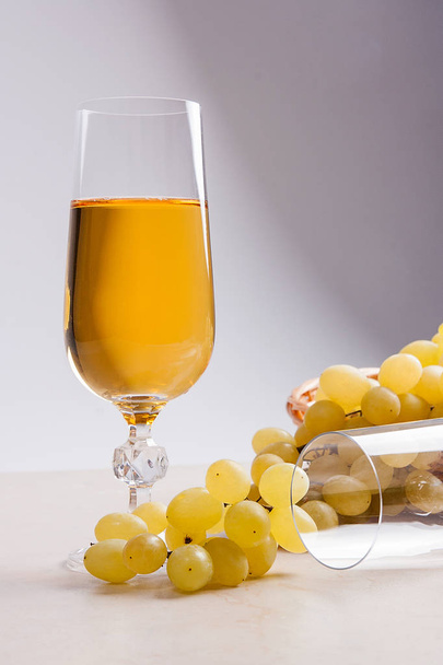 Λευκό κρασί και σταφύλια. Λευκό κρασί σε ποτήρι και σταφύλια σε φως m - Φωτογραφία, εικόνα