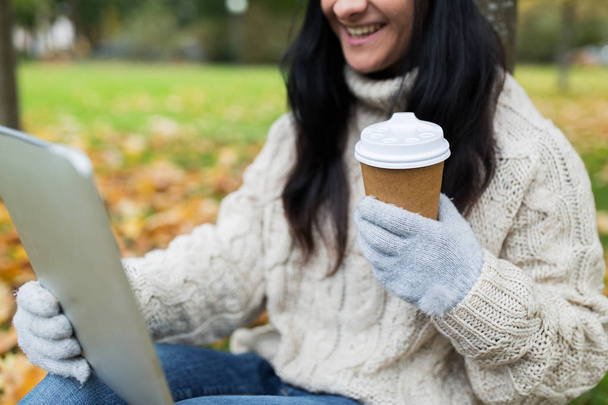 woman with tablet pc and coffee cup in autumn park - Foto, Imagem