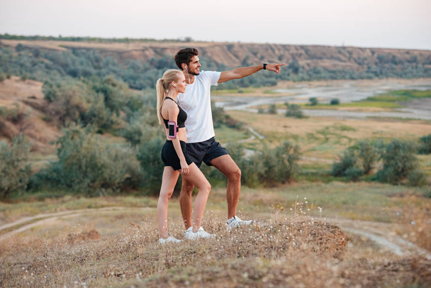 Fitness couple standing on a hill and looking at something - Foto, immagini