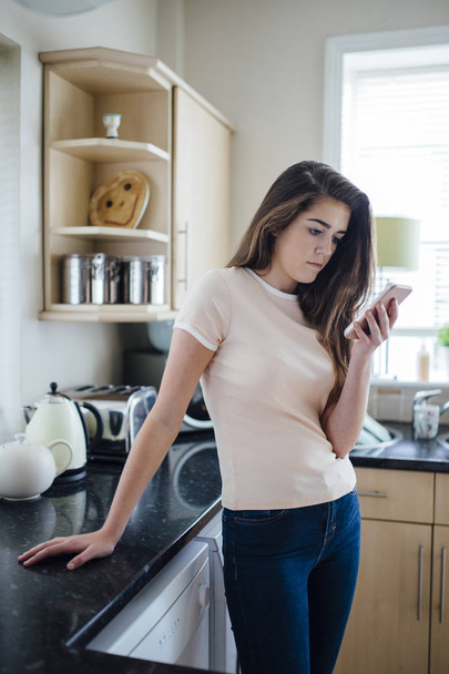Teenager Texting in the Kitchen - Foto, afbeelding