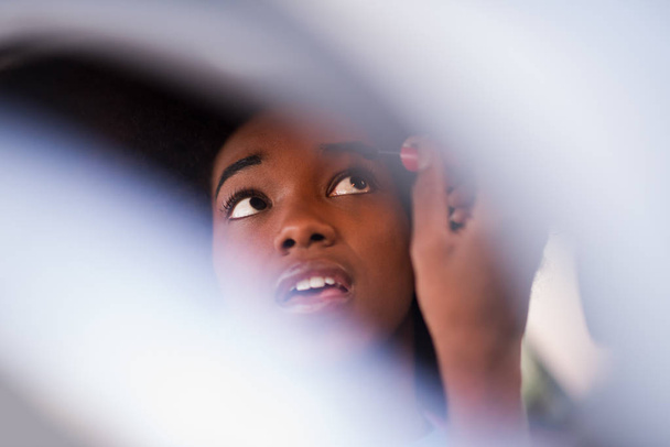 a young African-American woman doing makeup in the car - Foto, Imagem
