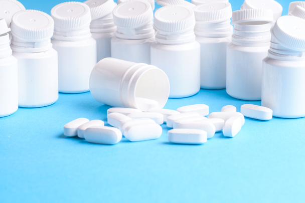 Muchas pastillas y tabletas aisladas sobre fondo azul claro
 - Foto, Imagen