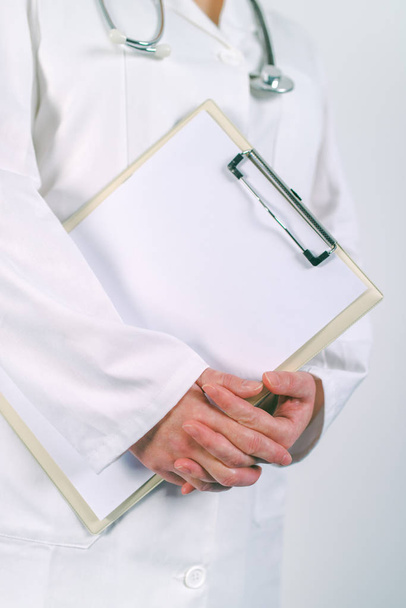 Femme médecin en uniforme blanc posant avec bloc-notes vierge
 - Photo, image