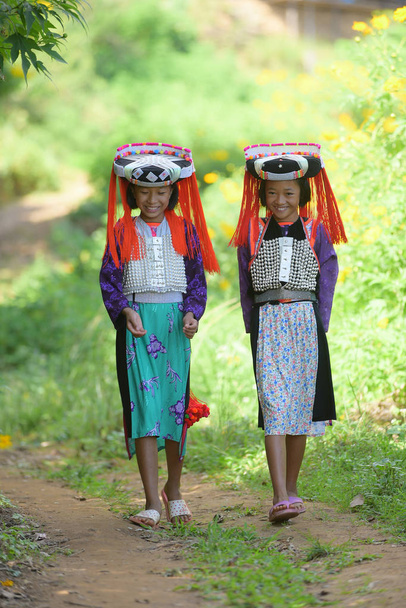 Dos hermosas chicas de la tribu Lahu asiáticas jóvenes en vestido personalizado caminar en la aldea con sonrisa y feliz
. - Foto, Imagen