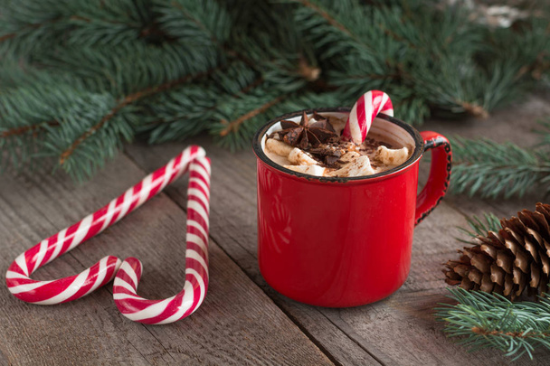 Hot chocolate with marshmallows on the wooden background fir-tree. Christmas tree with candy cane and mug with coffee. Hot cocoa with marshmallows. New Year. Holiday card. Rustic style. - 写真・画像