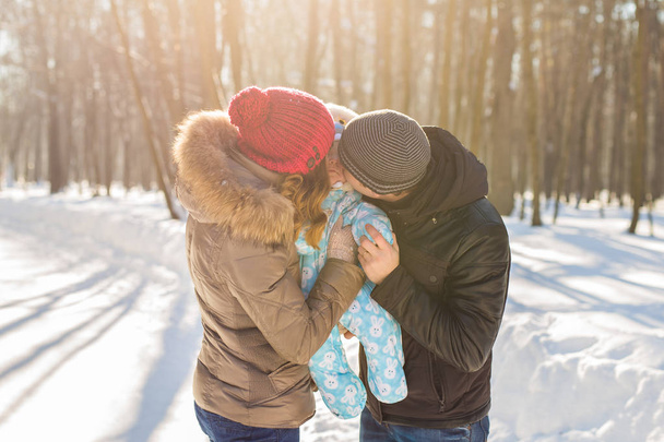 matka a otec drží jejich chlapeček a líbat jeho venku v zimě - Fotografie, Obrázek