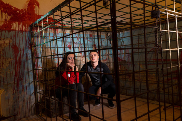 Couple of afraid Halloween victims imprisoned in a metal cage wi - Photo, image