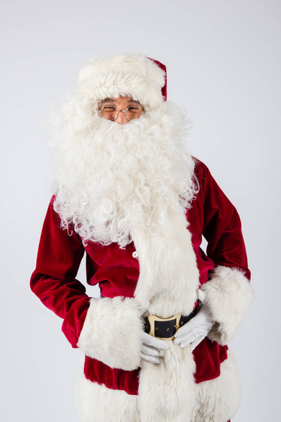 Santa Claus in eyeglasses and red costume standing on white background and looking into camera.  - Photo, image