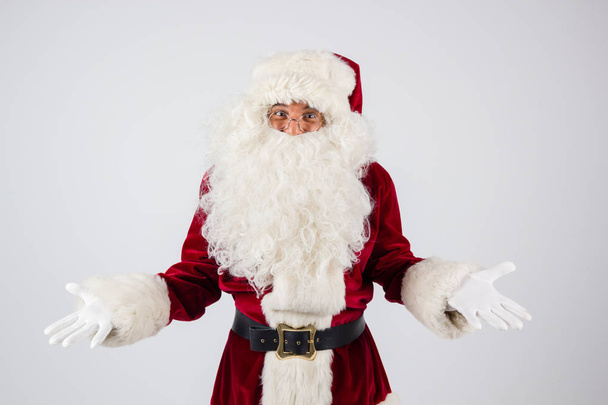 Santa Claus in eyeglasses and red costume throwing up hands on white background and looking into camera.  - Fotoğraf, Görsel