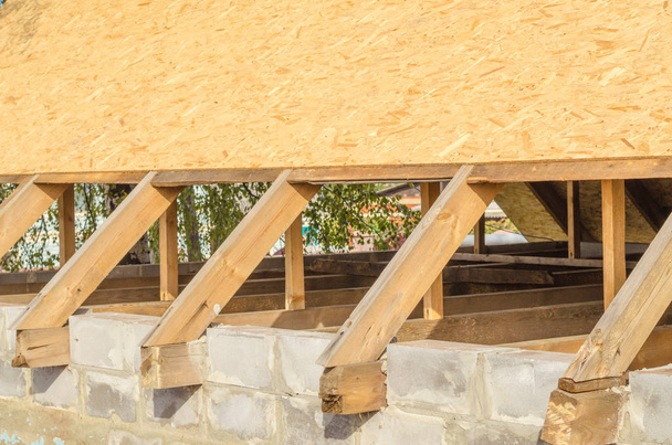 Nostaminen katto ristikko toiseen kerrokseen uuden asuinrakentamisen. Sisätilojen näkymä puinen kattorakenne. OSB-levyjen kattojen valmistelu
. - Valokuva, kuva