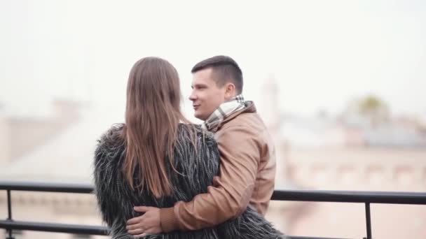 Back view of a couple on a roof of a building in a city. Lovers talk, laugh have great time together, enjoy the view - Кадры, видео