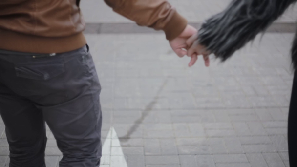 Mensen in gelukkige relatie. Backview van een verliefde paar hand in hand, lopen buiten samen, glimlachend en praten - Video